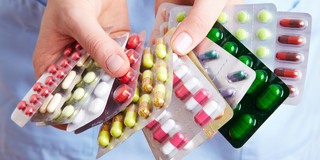 Auf dem Bild sind zwei Hände zu sehen, die mehrere Packungen Tabletten halten. 