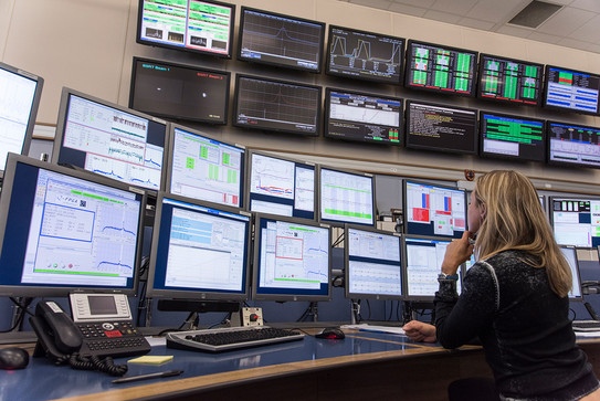 A woman sits in front of a multitude of monitors
