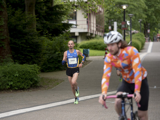 A man in sports outfit is running. A cyclist can be seen in the foreground.