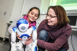 Eine Frau und ein Mädchen halten einen Roboter in den Händen.