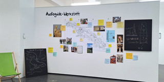A map, photos and colorful pieces of paper with information hang on a wall