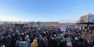 Numerous people at a demonstration against right-wing on the Platz der Deutschen Einheit in Dortmund with the main station in the background