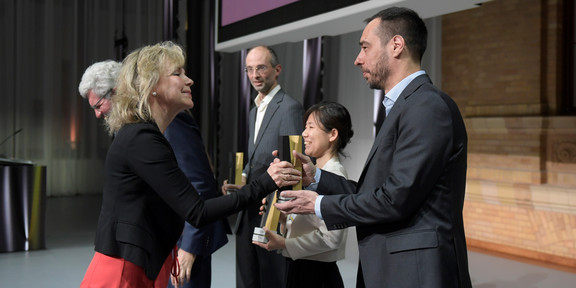 A woman is giving a black and gold trophy to a man on a stage.