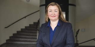 Ein Foto von Prof. Liudvika Leišytė: Einer Frau mit langen Haaren in einer Bluse und einem grauen Blazer.