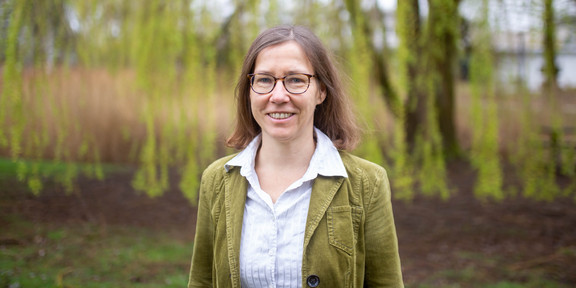 A portrait photo of a woman with glasses and a white blouse on the TU Dortmund campus.