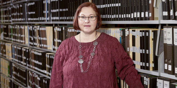 Portrait of Stephanie Marra in front of a shelf with files. 