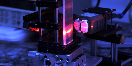 Eine Detailaufnahme eines Lasers im Labor in roten und blauen Farben.