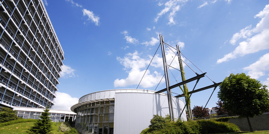 Panoramic view of the Audimax and the mathematics building against a blue sky.
