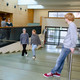Studierende im Seminargebäude 1, im Vordergrund steht ein Student am Geländer und schaut auf zwei andere Studierende, die die Treppe hochgehen.