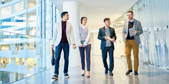 Kooperationen Vier Studierende laufen nebeneinander durch einen hellen Gang