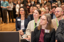 Das Bild zeigt Personen im Publikum, die dem Progamm interessiert folgen.