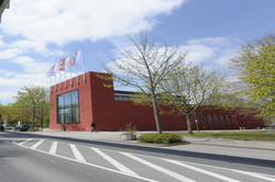 The red International Meeting center building with the H-Bahn next to it in spring time