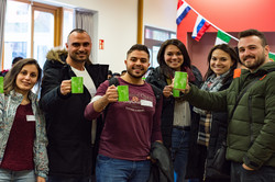 A group of international students holding green TU Dortmund University coffee cups