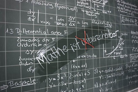 Tafel mit Formeln in der Mitte steht: Mathe ist unberechenbar