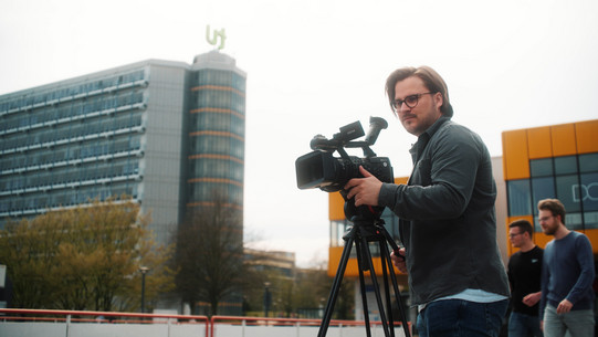 Ein Student steht hinter einer Kamera.