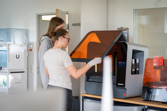 Von der Idee zum eigenen Start up Zwei Personen stehen vor einem 3D-Drucker.