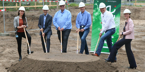 Groundbreaking ceremony for the DDIC expansion building Six people are standing with spades in their hands behind a small pile of heaped up earth.
