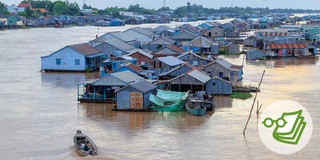 Vietnam Häuser im Wasser Häuser stehen im Wasser in Vietnam und links unten fährt ein kleines Boot.