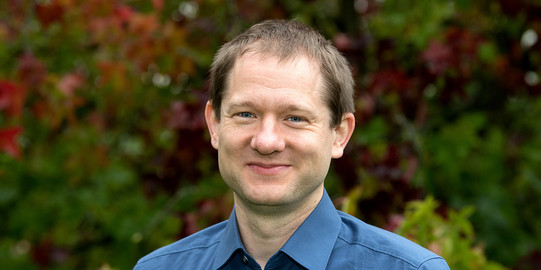 Porträt von JProf. Nils Weitzel: Nils Weitzel trägt ein blaues Hemd und lächelt in die Kamera.