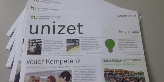 Several copies of an issue of the unizet newspaper lie fanned out on a table