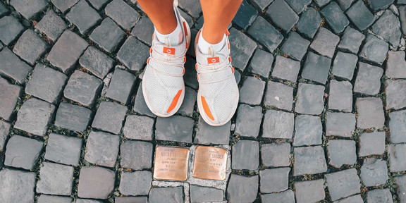 Gedankengänge Vogelperspektive von zwei Stolpersteinen und zwei Paar Beinen