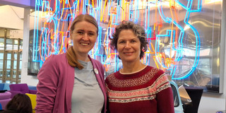 Photo: Prof. Doris Reiter and Dr. Christiane Wüllner stand in a room in front of colorful neon signs.