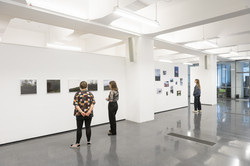 Drei Besucherinnen betrachten verschiedene Fotos der Ausstellung.