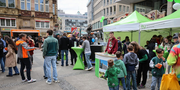 Auf dem Foto sieht man den Infostand der TU Dortmund in der Innenstadt sowie zahlreiche Besucher*innen.