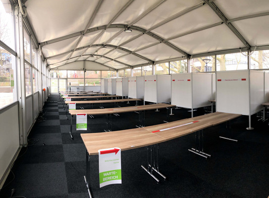 Teststation TU Dortmund Innenansicht eines Zelts mit mehreren Coronateststraßen und Testkabinen
