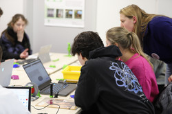 Schüler*innen sind von hinten zu sehen, wie sie auf einen Laptop gucken