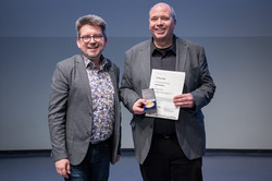 Foto: Markus Alex (ITMC) überreicht Uwe Grützner den Lehrpreis für lehrunterstützendes Engagement von Mitarbeitenden in Technik und Verwaltung.