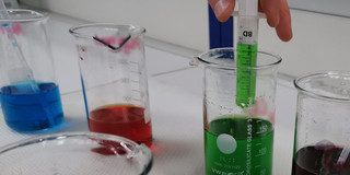 Four flasks with differently colored water stand on a table.