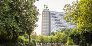 Das Foto zeigt den Mathe-Tower auf dem Campus der TU-Dortmund umsäumt von Bäumen.