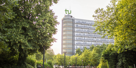 Das Foto zeigt den Mathe-Tower auf dem Campus der TU-Dortmund umsäumt von Bäumen.