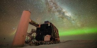 The IceCube laboratory in front of an impressive starry night sky, which also shows the Milky Way.