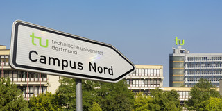 Schild weist den Campus Nord aus. Im Hintergrund das Mathematikgebäude der TU Dortmund