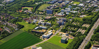 Zu sehen ist ein Luftbild von der TU Dortmund und FH Dortmund sowie umliegende Siedlungen, Straßen und Grünflächen.