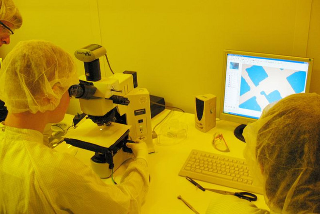 Die Teilnehmenden schauen sich im Reinraum eine Probe durch ein Mikroskop an