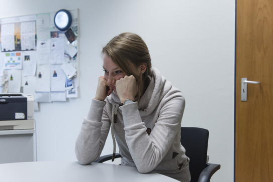 2018_Zentrale_Studienberatung_03 Junge Frau sitzt frustriert am Schreibtisch mit aufgesetzten Ellbogen.