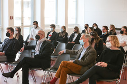 Eine Gruppe von Frauen und Männern sitzen vor einer Leinwand und hören einem Vortrag zu.