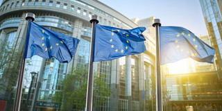 3 EU flags flying in front of the EU Parliament in Brussels.