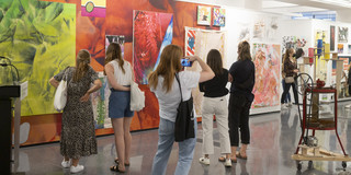 Mehrere Personen schauen sich ein großes rotes Bild einer Kunstausstellung an.