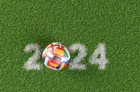 Photo: Soccer ball with the flags of several countries that have qualified for the 2024 European Soccer Championship. The year 2024 as a chalk mark on the pitch.