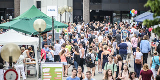 Viele Menschen schlendern in sommerlicher Kleidung über die Mensabrücke. Rechts und links sind Stände aufgebaut.