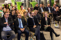 People in suits and blazers sit in the audience.