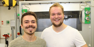 Zwei Männer stehen in einer Werkstatt 