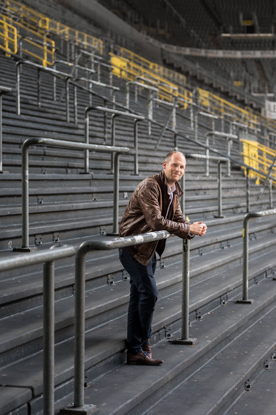 Aufnahme eines Mannes, der an einen Wellenbrecher gelehnt auf einer Tribüne steht