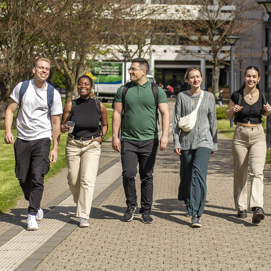 Photo: Five students stroll across the sunny campus of TU Dortmund University.