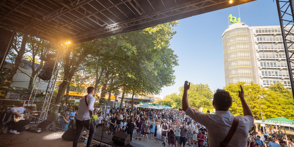 Sommerfest 2022 Eine Band spielt und singt vor Zuschauer*innen auf einer Bühne.