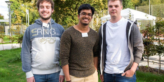 Drei junge Männer stehen neben einander.